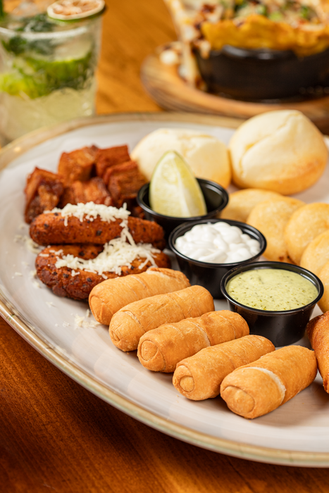 Image of a plate with tequeños, salsa, and arepas