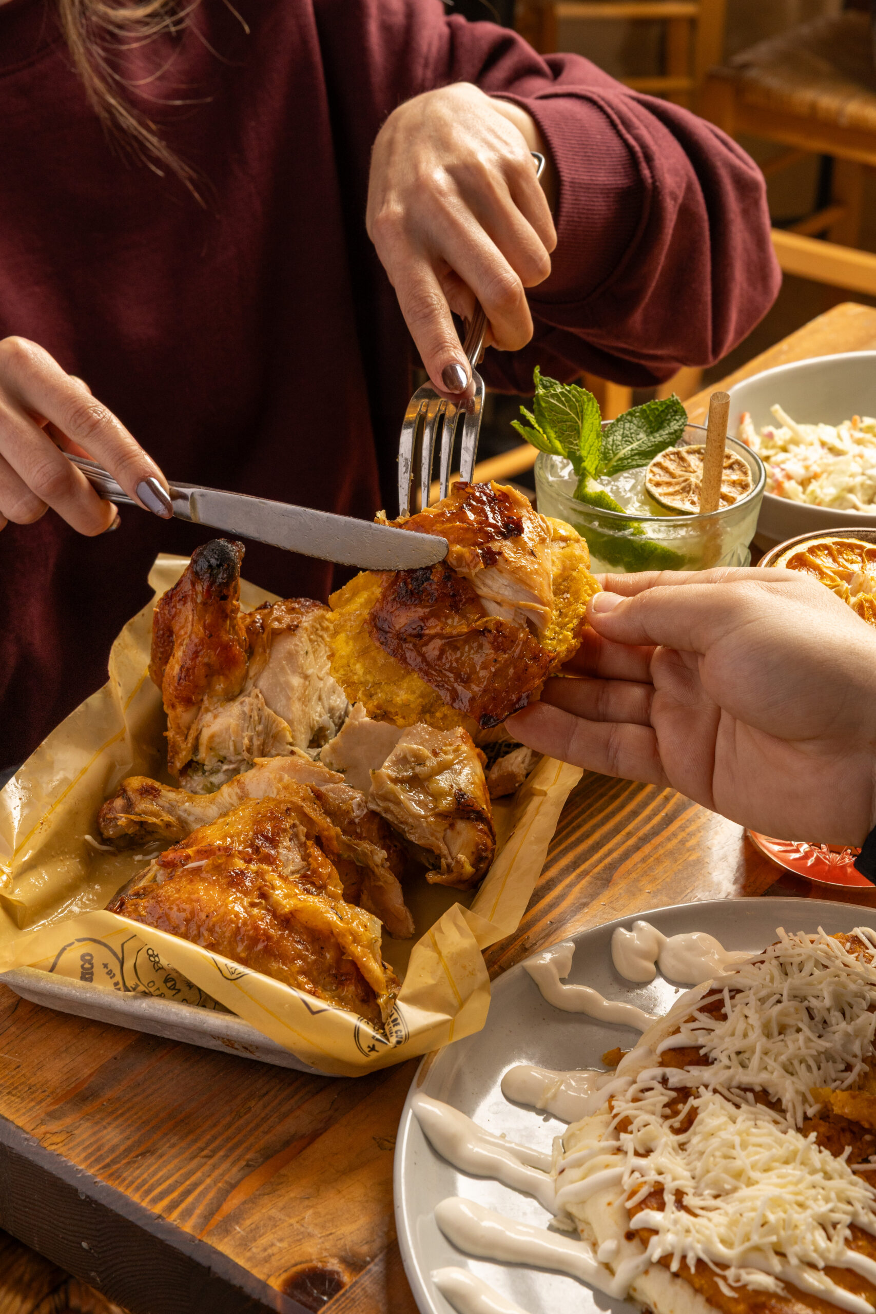 A close-up shot of one person cutting a piece of chicken and another person holding the piece of chicken.