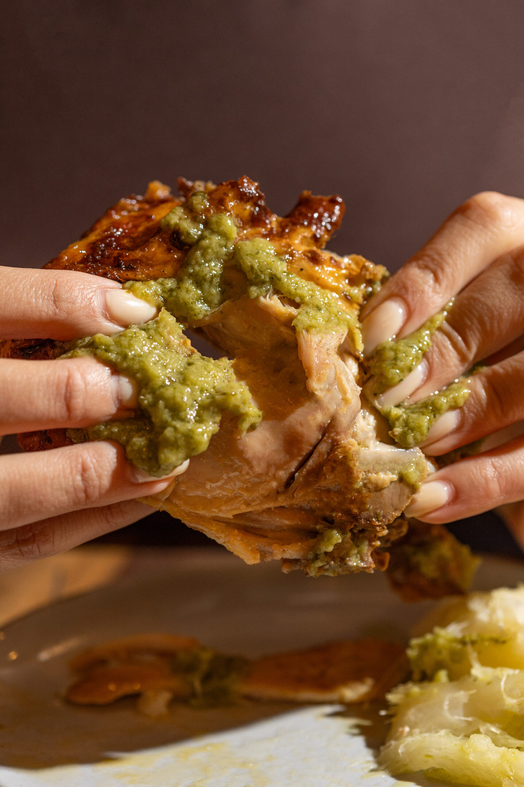 A close-up image of a person holding a piece of chicken with both hands.